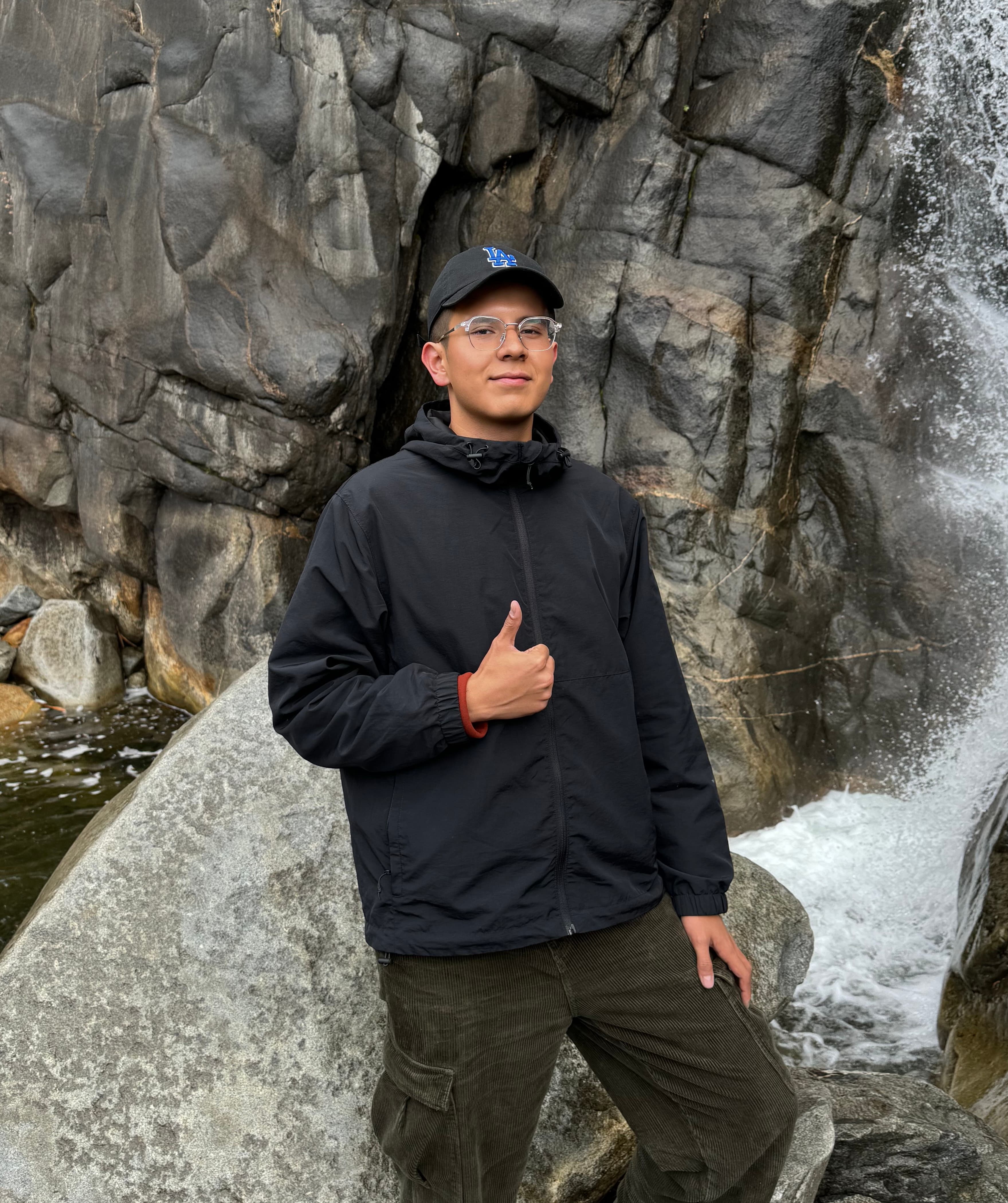 Brian Wumutijiang standing by a rocky waterfall